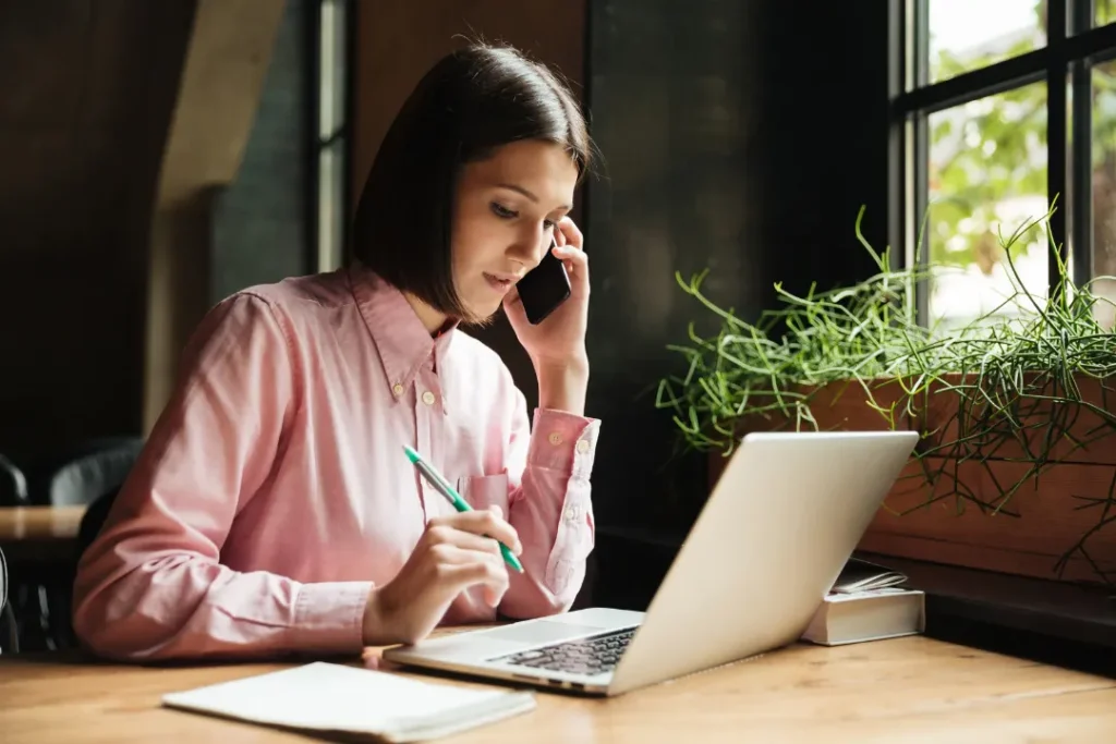 Female technical writer on a phone call in front of her laptop. remote freelance writing jobs